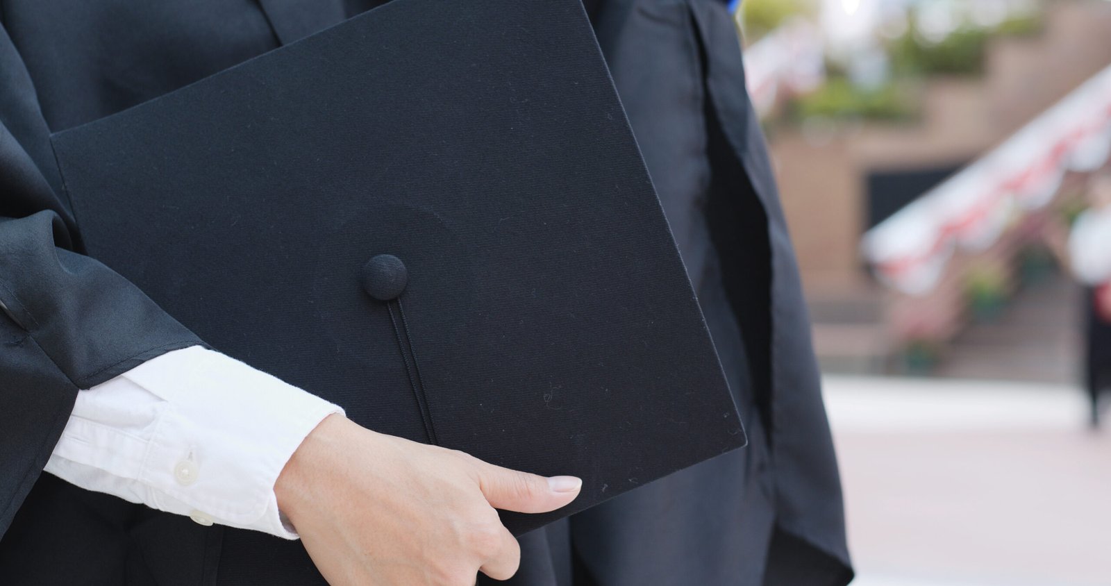 woman wearing graduation gown and holding mortarboard